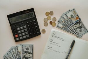 Flat lay of calculator, cash, coins, and handwritten notes for budget planning.