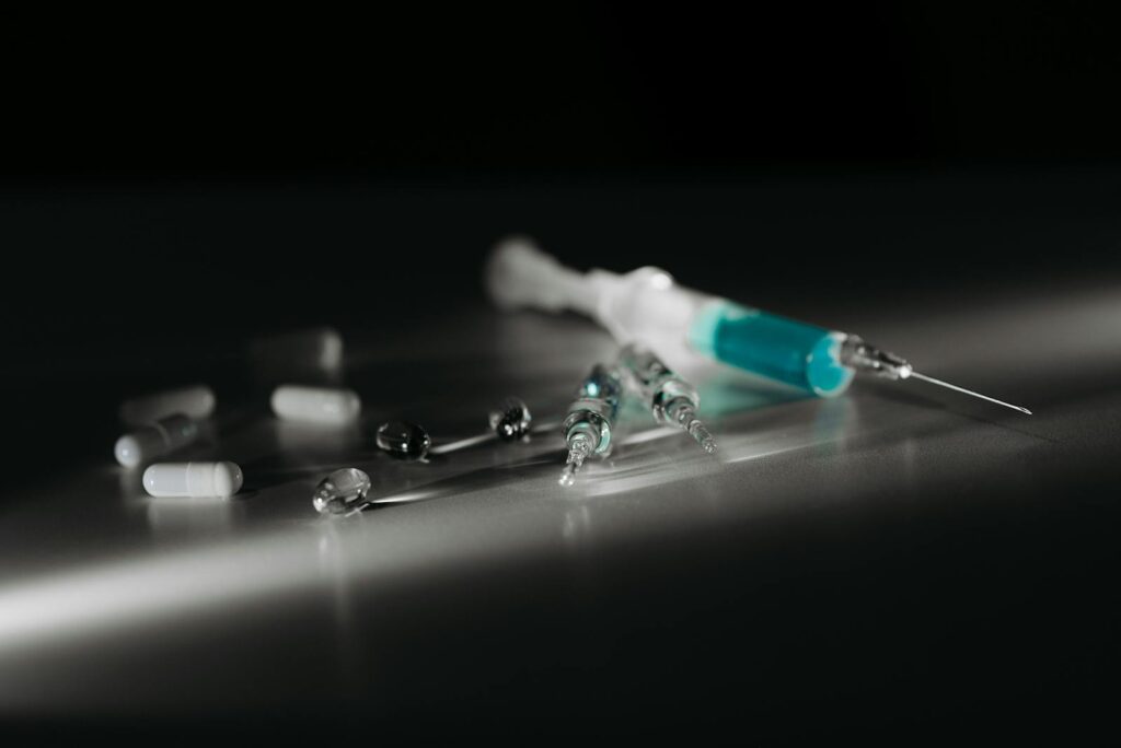 Close-up of syringes and capsules in selective focus with dramatic lighting.