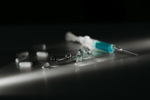 Close-up of syringes and capsules in selective focus with dramatic lighting.