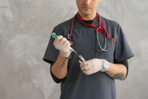 A healthcare worker in scrubs prepares a syringe with precision.
