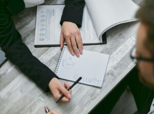 Close-up of a business meeting with hands over paperwork, graphs, and documents.