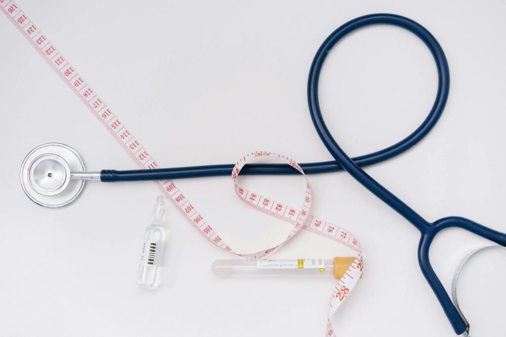 A stethoscope, ampoule, and tape measure on a white background symbolize healthcare essentials.