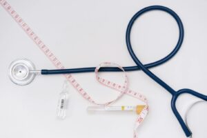 A stethoscope, ampoule, and tape measure on a white background symbolize healthcare essentials.